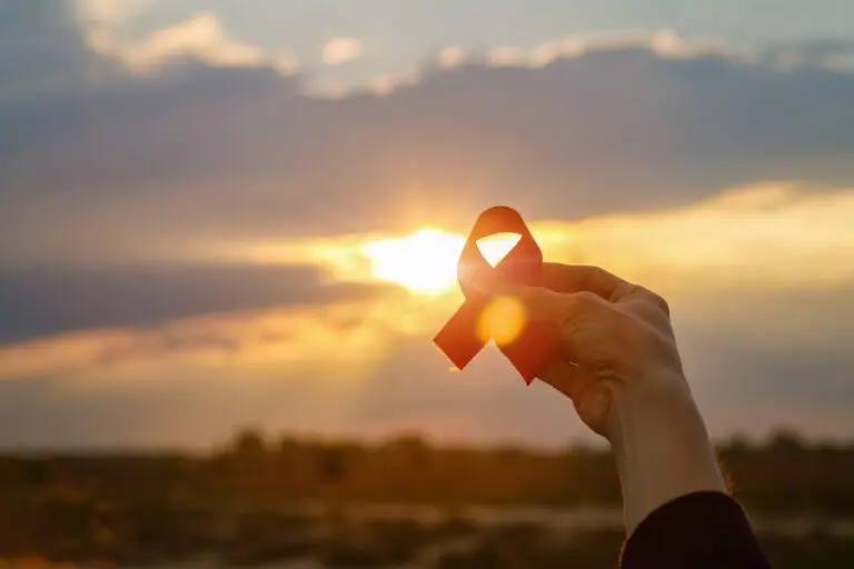 Hand holding ribbon sunset